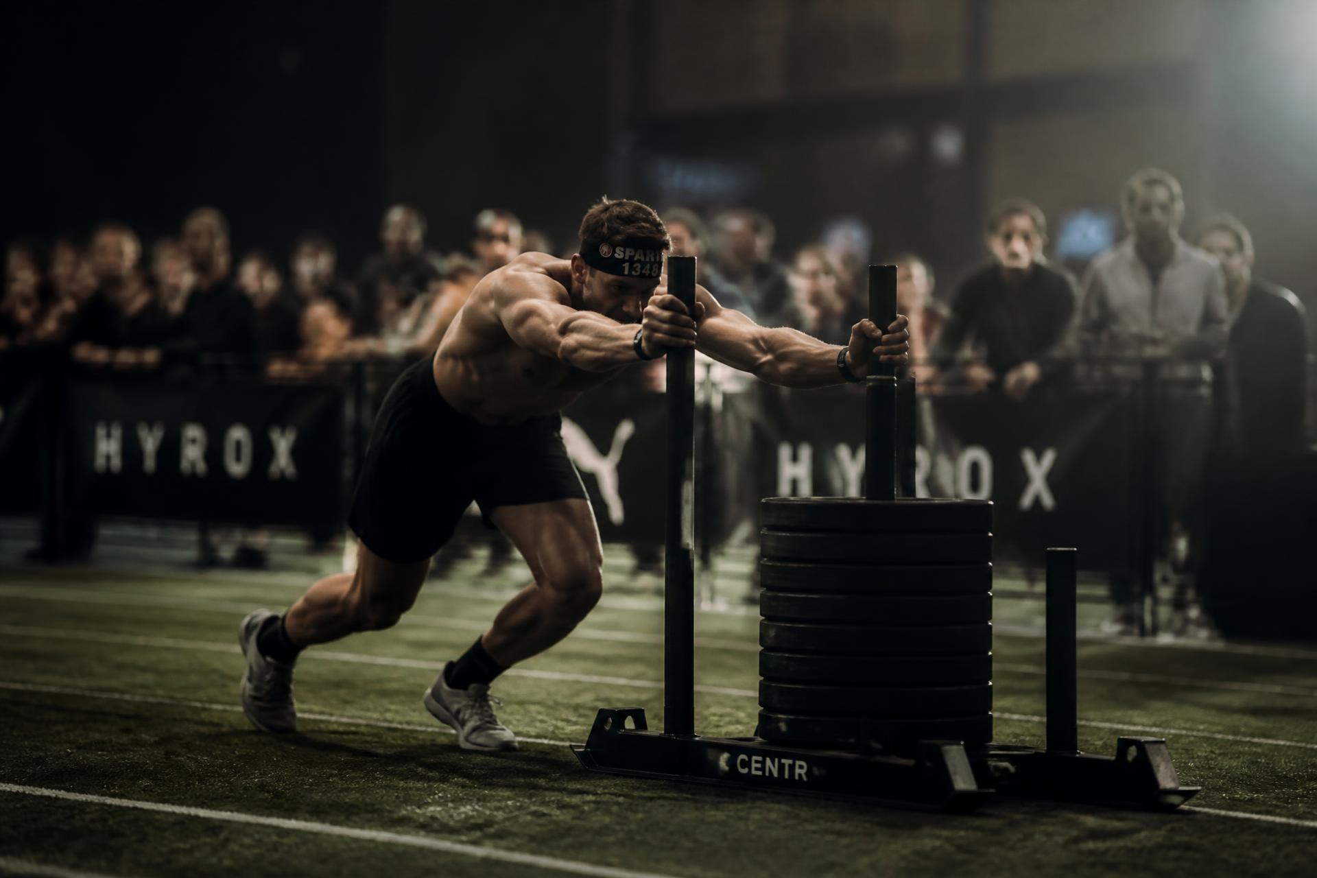 Athlete pushing a loaded sled during an indoor fitness race